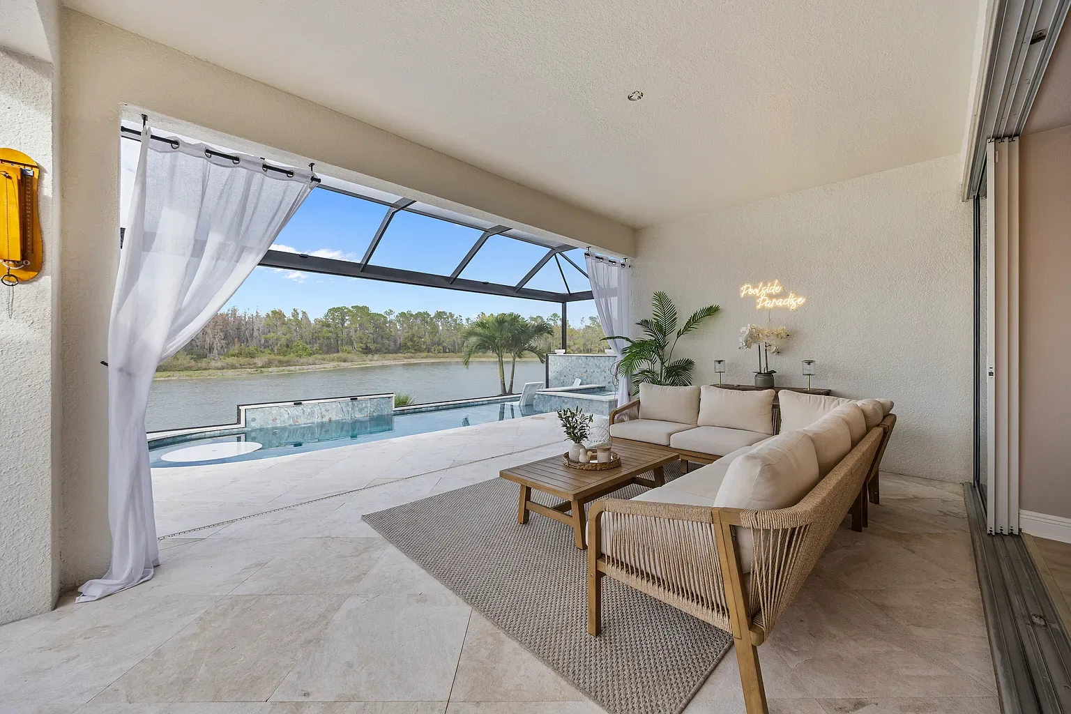 Covered poolside seating area with sheer curtains and a lake view, Wesley Chapel, Florida.