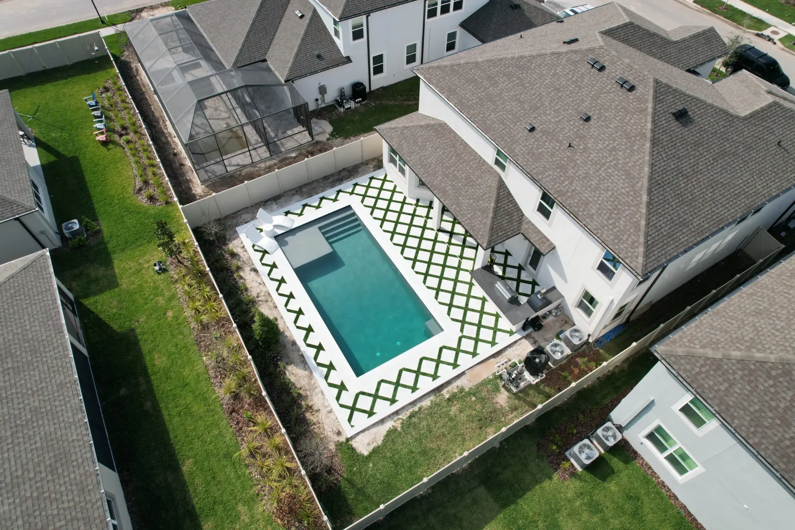 Aerial view of a rectangular pool and freshly laid sod in a diamond pattern beside the home.